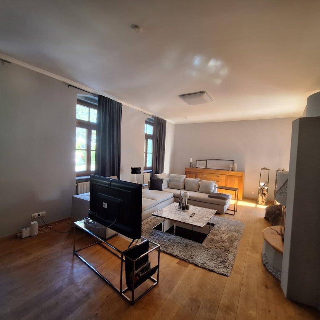 Helles Wohnzimmer mit großem Ecksofa, Holzboden und großen Fenstern.