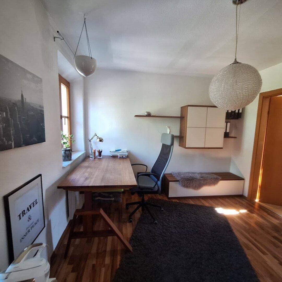 Helles Arbeitszimmer mit Holztisch, Bürostuhl und Holzboden.