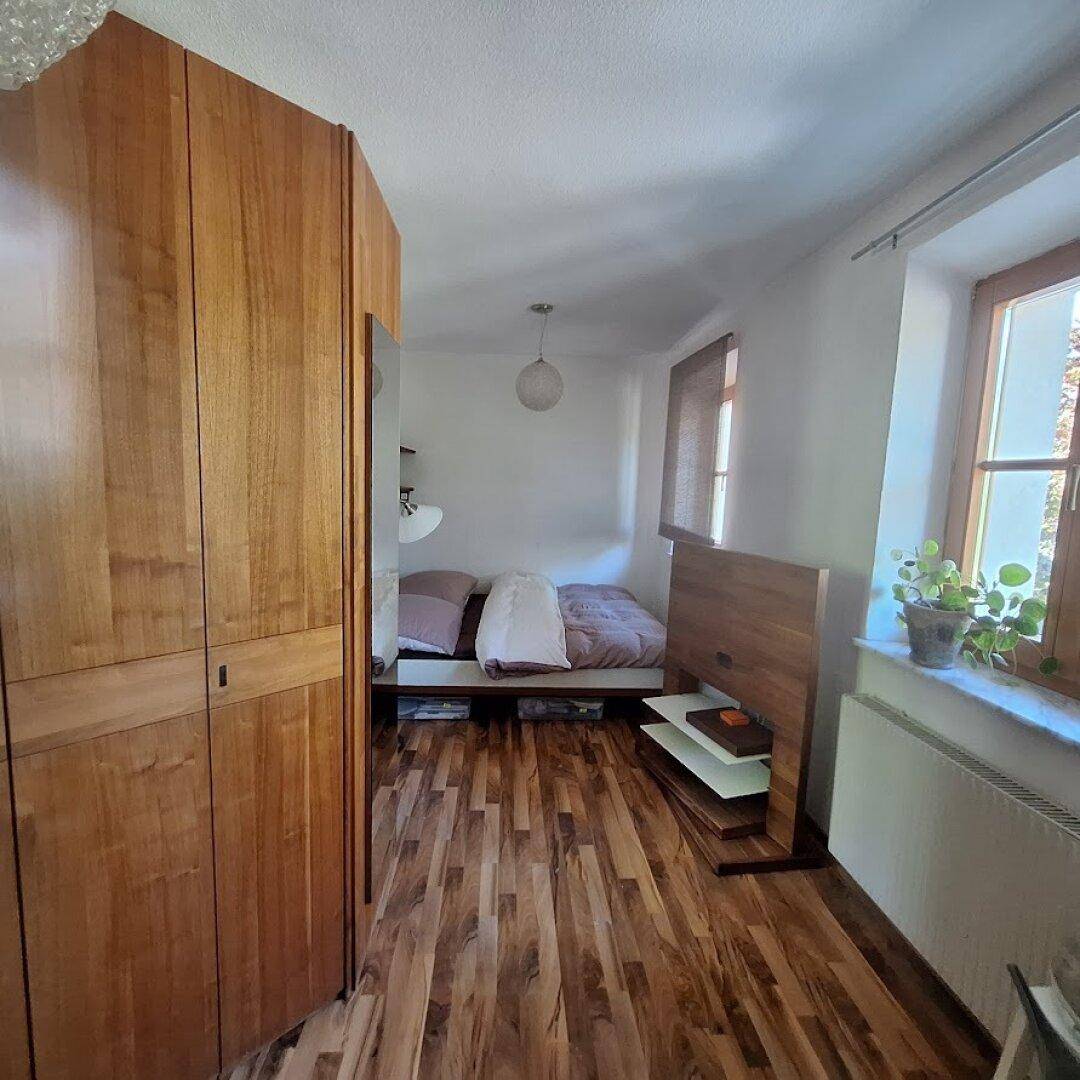 Gemütliches Schlafzimmer mit Holzboden, Einbauschrank und Fenster.