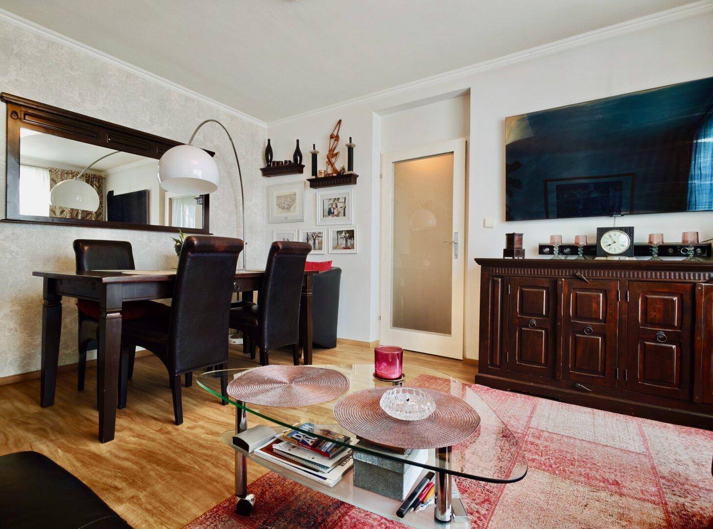 Wohn-Essbereich mit Esstisch, großem Spiegel und einem Sideboard unter dem Fernseher.