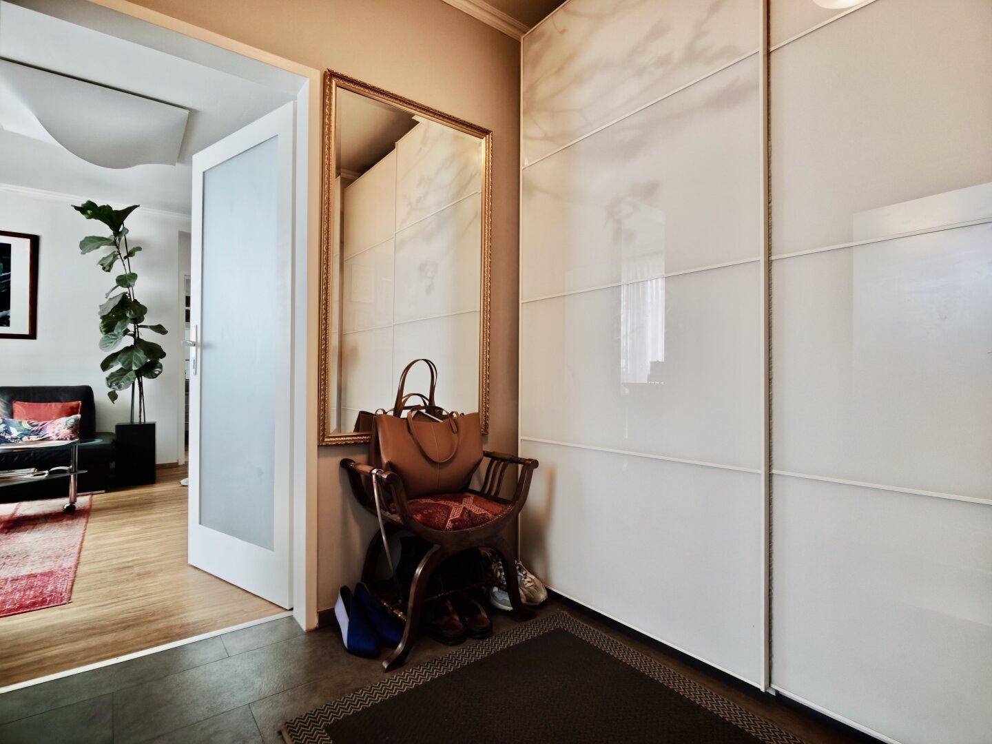 Flur mit großem Spiegel, Garderobe und Zugang zum Wohnbereich.