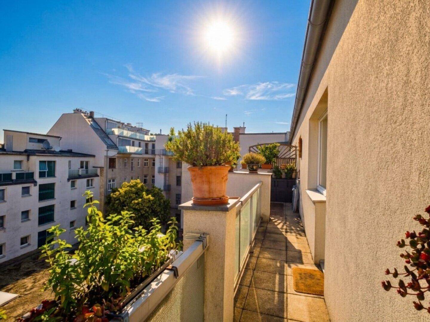 Sonniger Balkon mit vielen Pflanzen und einem weiten Blick über die Stadt.