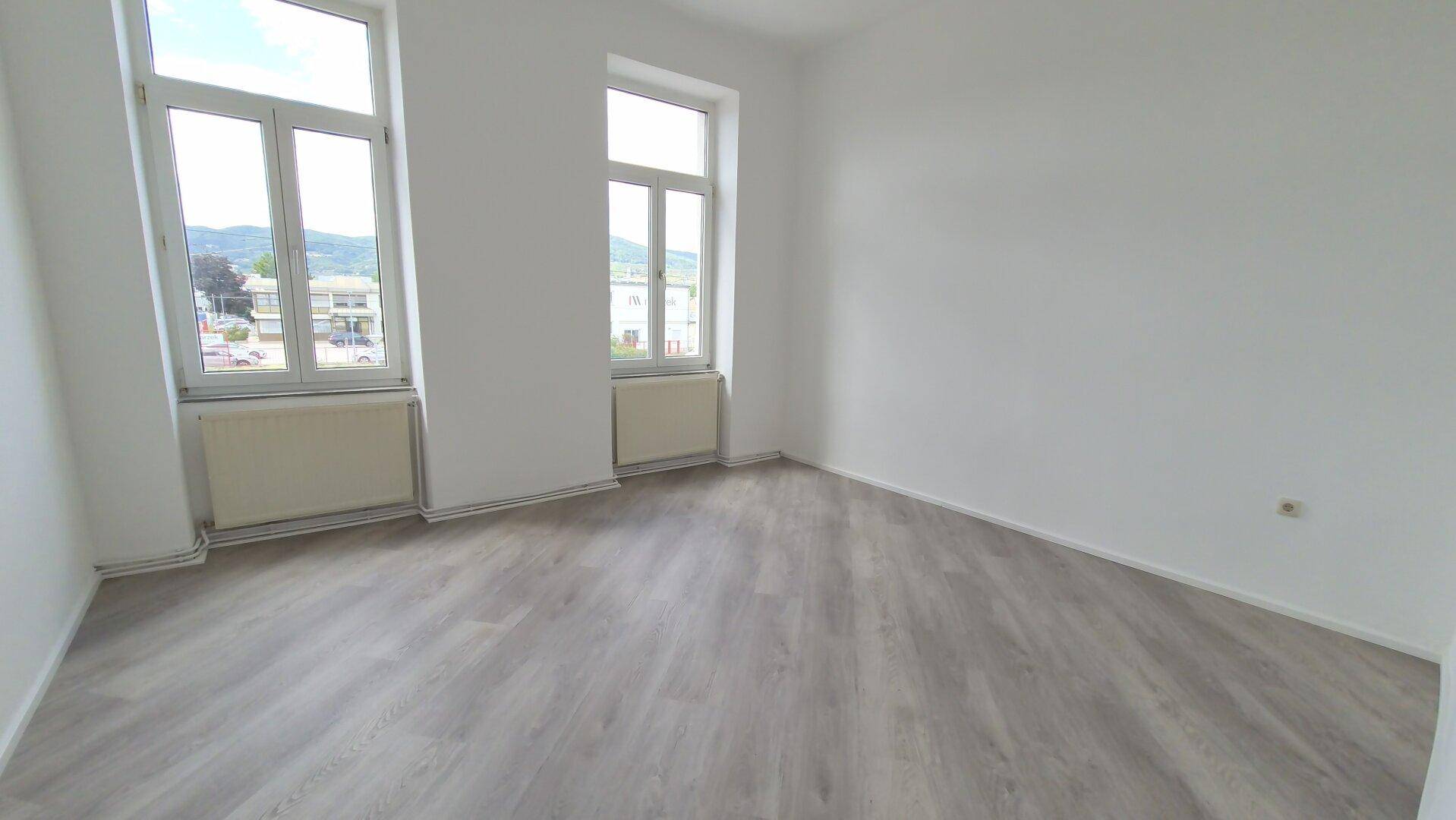 Geräumiges Zimmer mit hellem Laminatboden, weißen Wänden und weitem Blick auf die Umgebung.