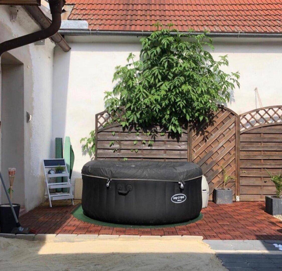 Gemütlicher Außenbereich mit aufblasbarem Whirlpool auf einer gepflasterten Terrasse.