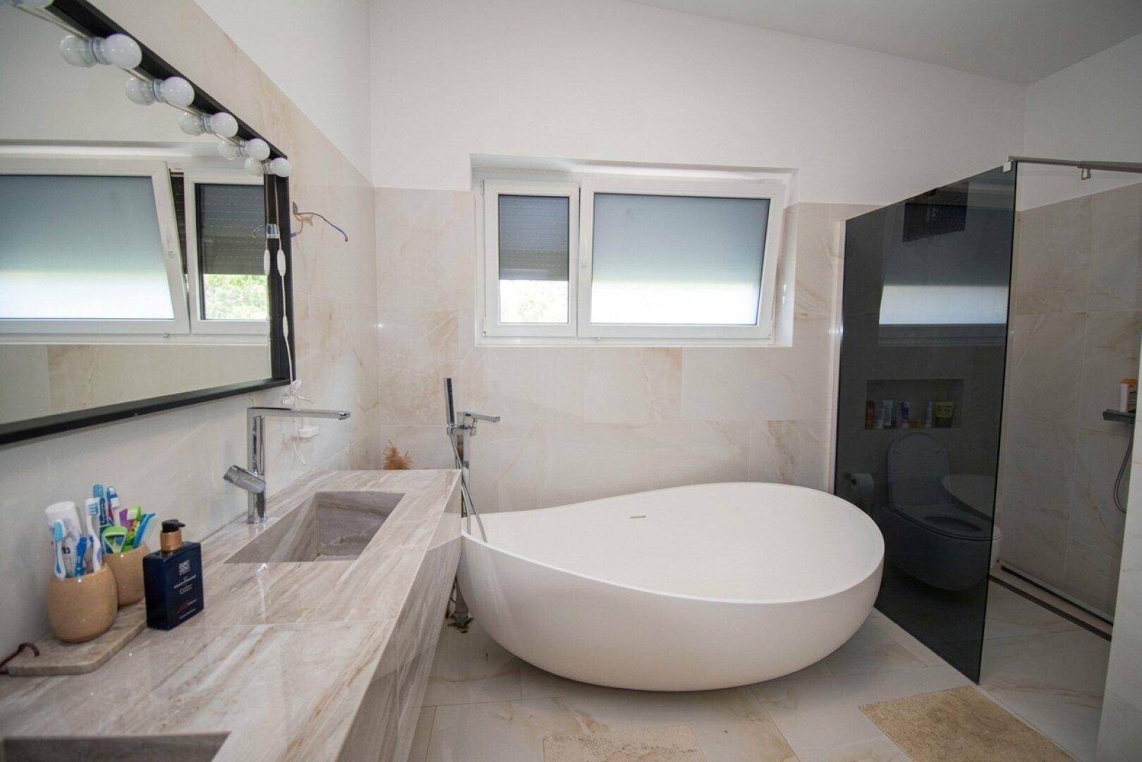 Modernes Badezimmer mit freistehender Badewanne, Marmorfliesen und begehbarer Dusche.