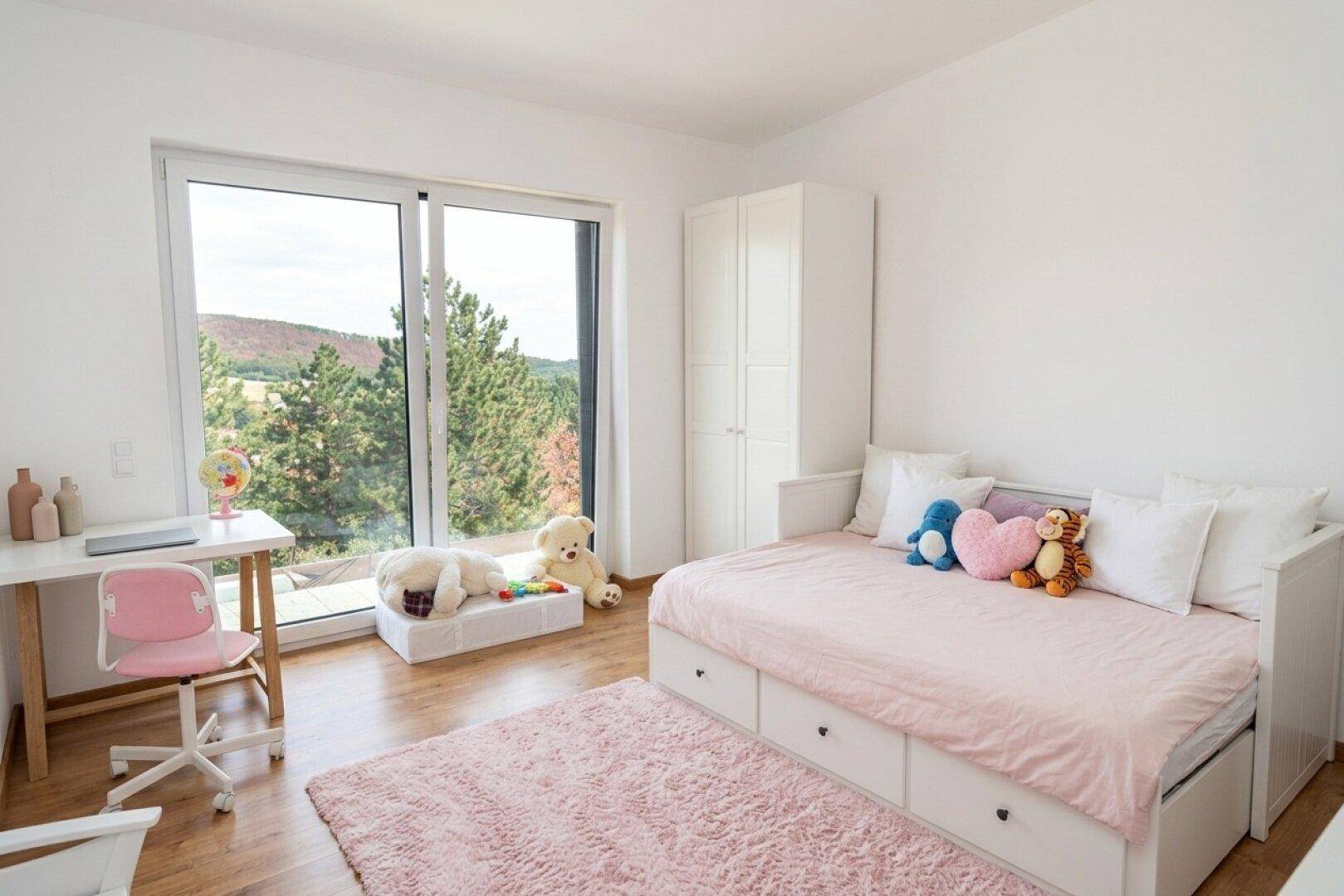 Helles Kinderzimmer mit Einzelbett, Schreibtisch und großem Fenster mit Blick ins Grüne.