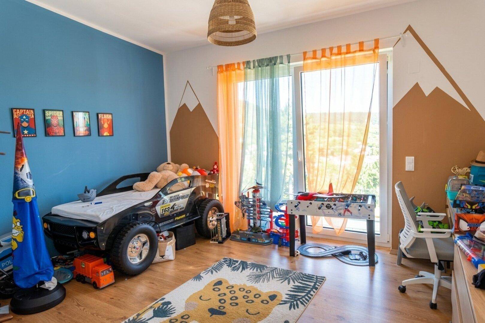 Farbenfrohes Kinderzimmer mit Autobett, Spielbereich und großem Fenster.