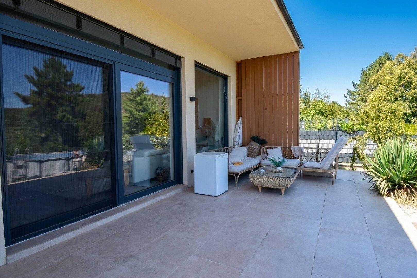 Geräumige Terrasse mit Fliesenboden, Loungemöbeln und Blick ins Grüne.