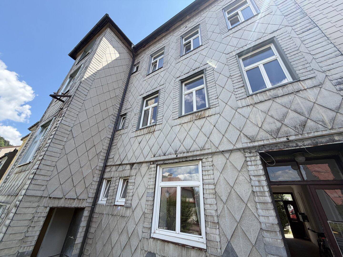 Ansicht der Gebäudefassade mit charakteristischer Schieferverkleidung und vielen Fenstern.