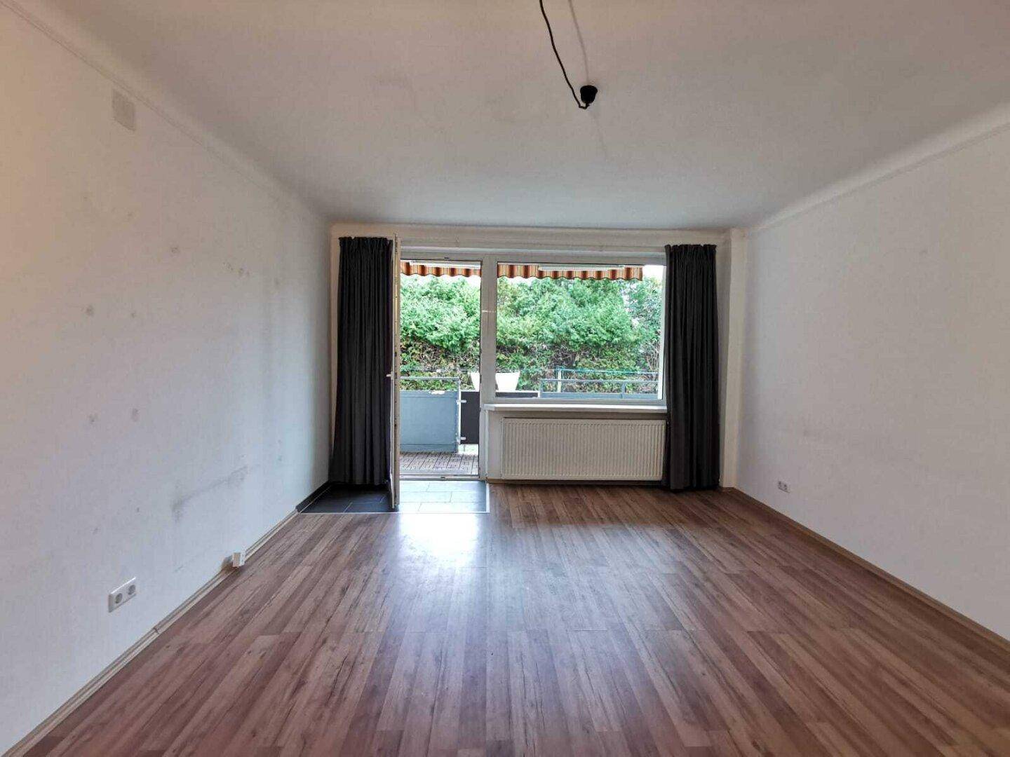 Geräumiges Zimmer mit Laminatboden und direktem Zugang zum Balkon.
