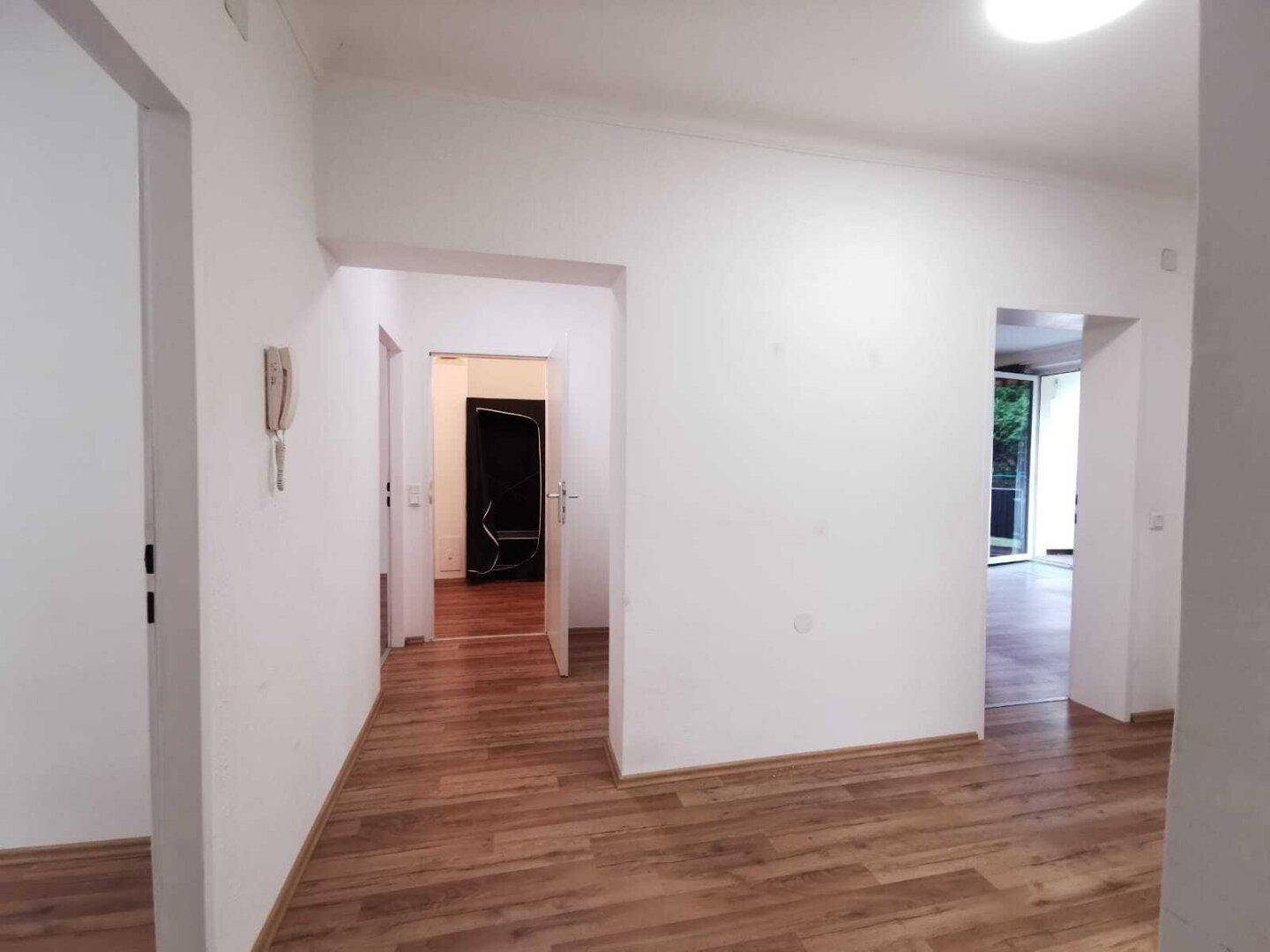 Geräumiger Eingangsbereich mit Laminatboden, der zu verschiedenen Zimmern führt.