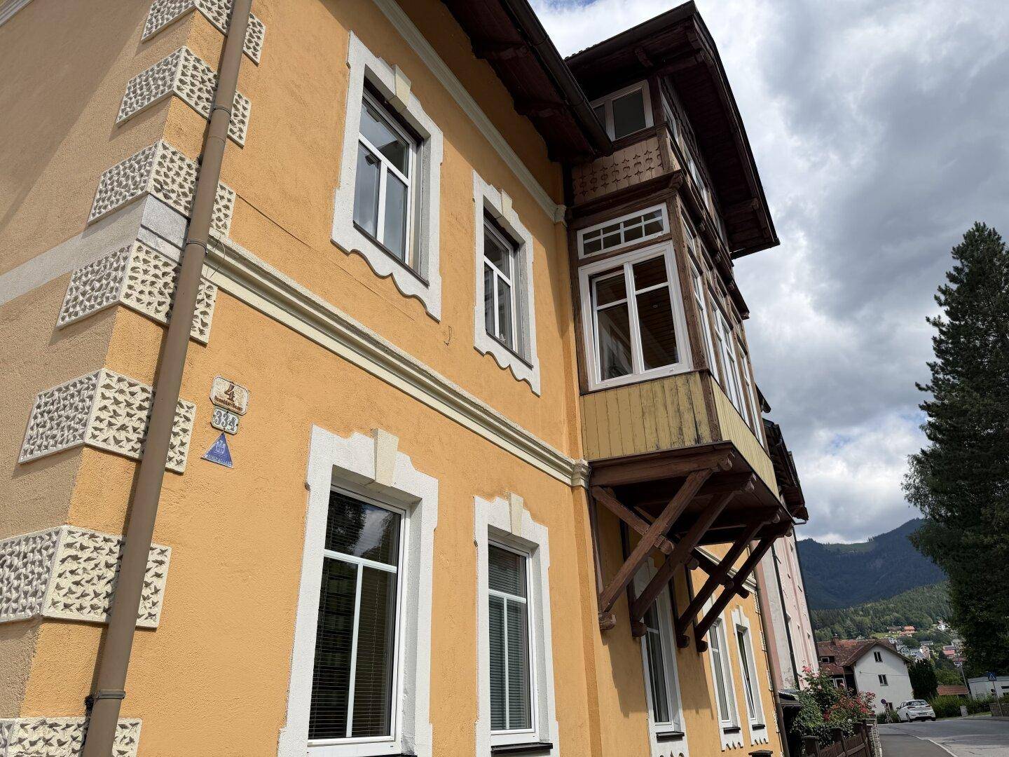 Detailansicht der historischen Fassade mit Erker und dekorativen Elementen unter bewölktem Himmel.