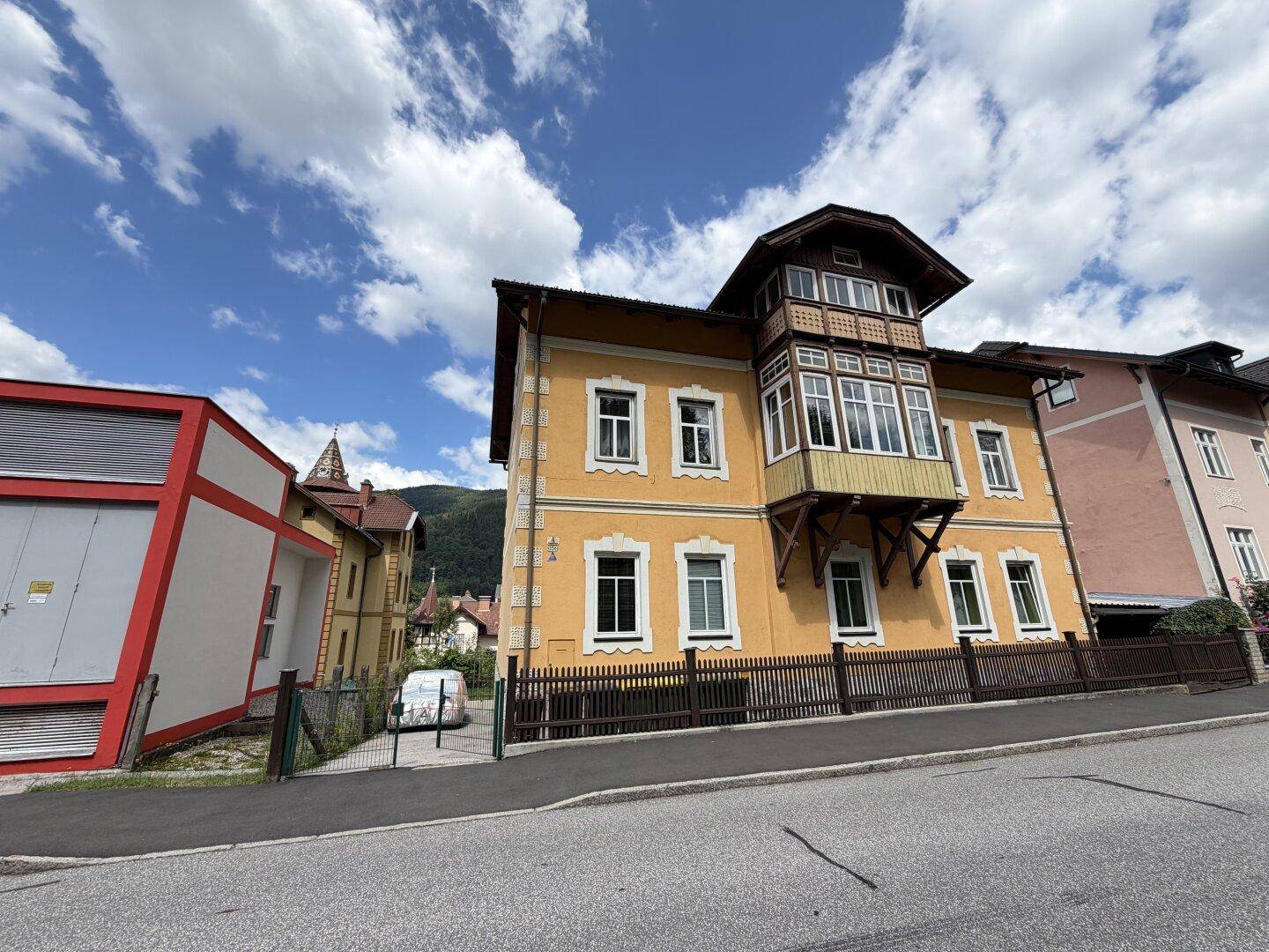 Ansicht des historischen Gebäudes von der Straße aus mit einem markanten Erker und Bergblick.