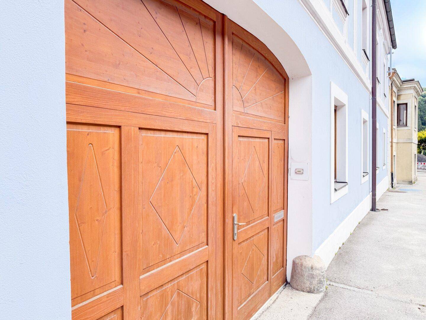 Nahaufnahme einer großen, verzierten Holztür an der Fassade des Gebäudes.