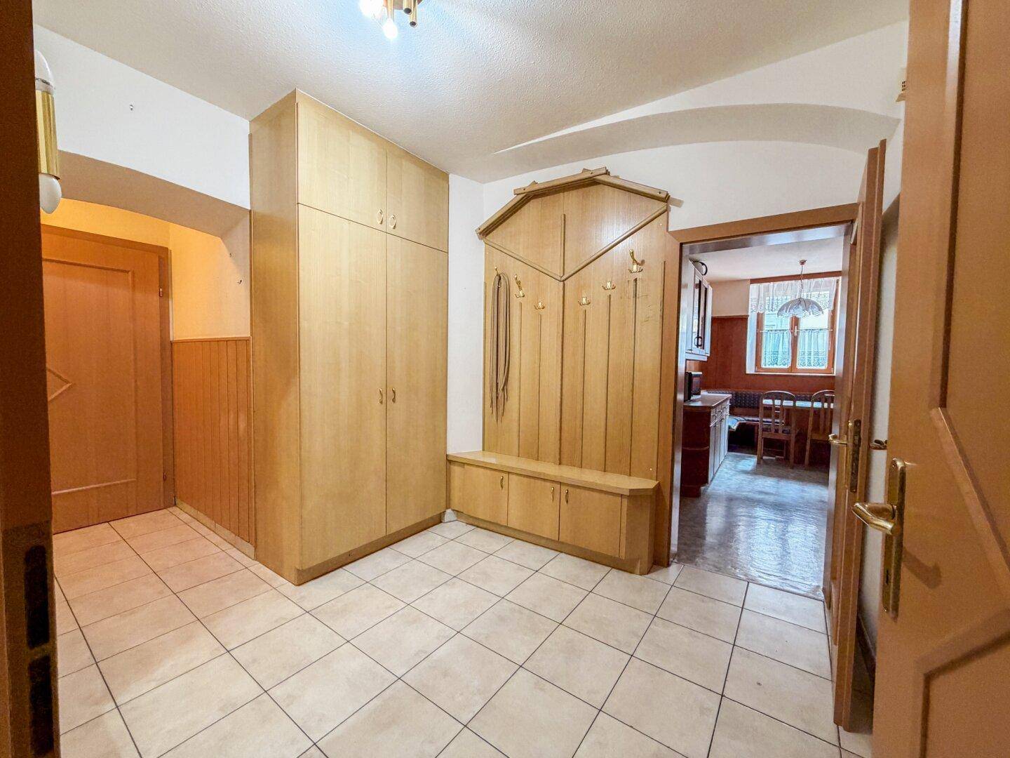 Eingangsbereich mit Fliesenboden, Holzmöbeln und Garderobe.