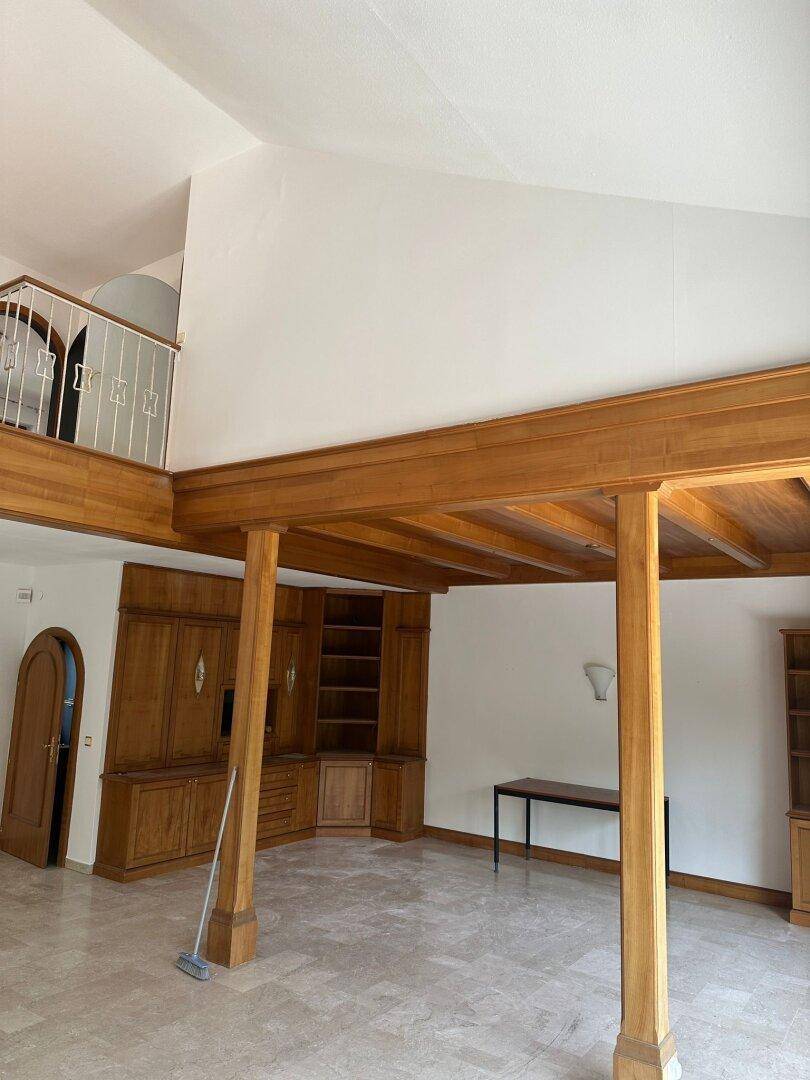 Großzügiges Wohnzimmer mit Holzbalken, Einbauschränken und Blick auf die Galerie.