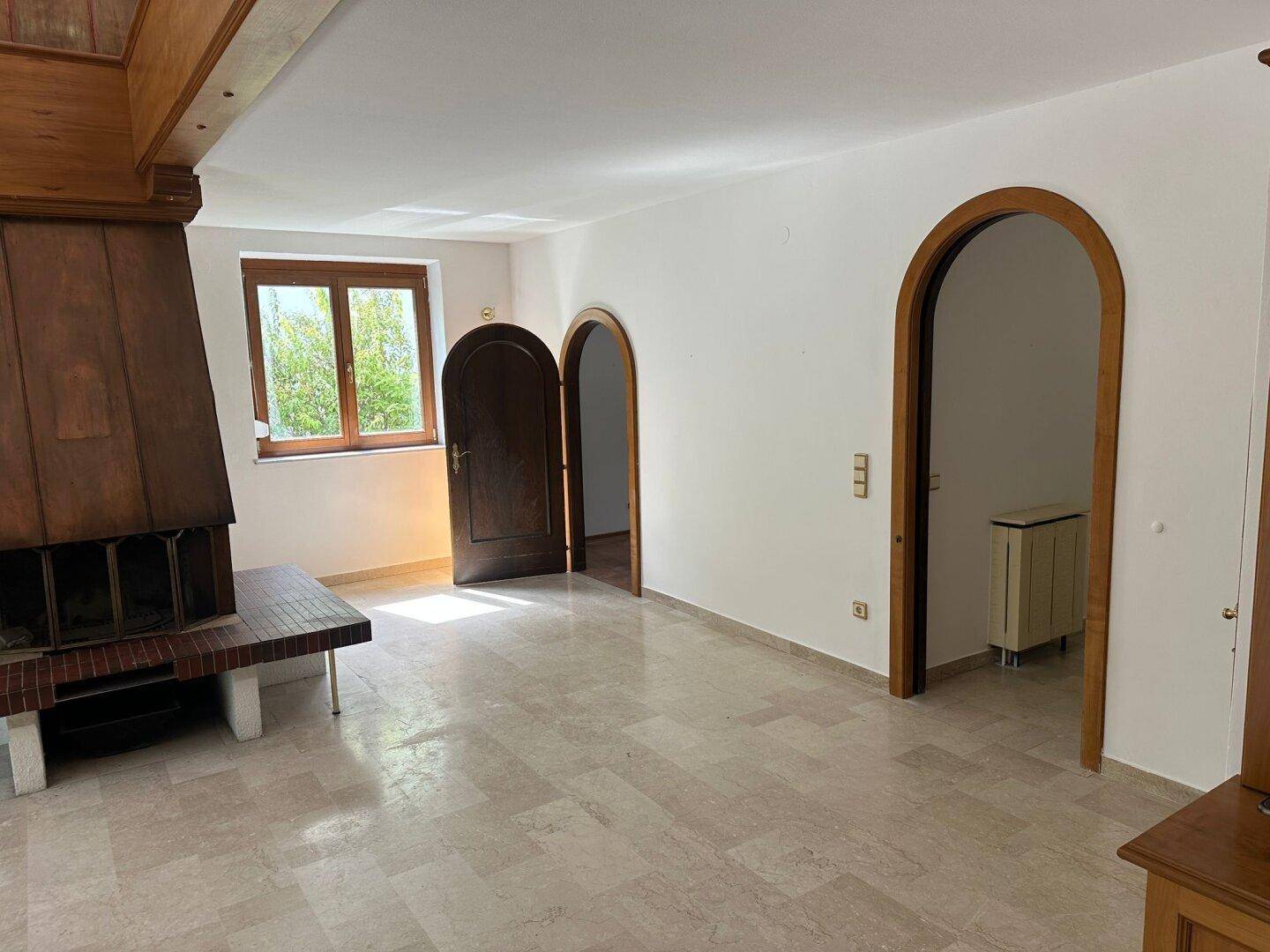 Gemütlicher Bereich mit Kamin, Fenster und eleganten Rundbogentüren.