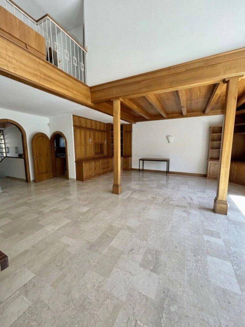 Geräumiges Wohnzimmer mit Holzbalken, Einbauschränken und Blick auf die obere Etage.