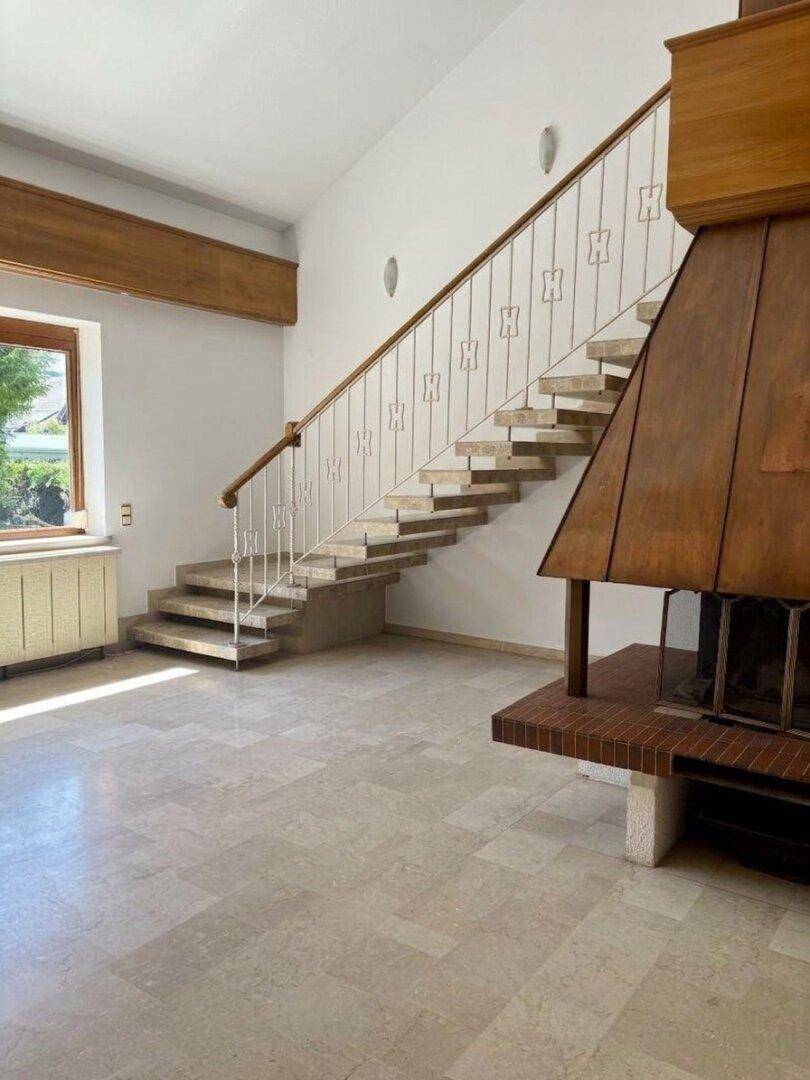 Detailansicht der eleganten Treppe und des Kamins im Wohnbereich.