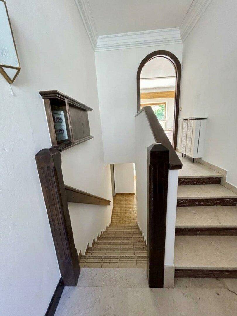 Treppenhaus mit Marmorstufen und einem eleganten Rundbogen, der zu einem weiteren Bereich führt.