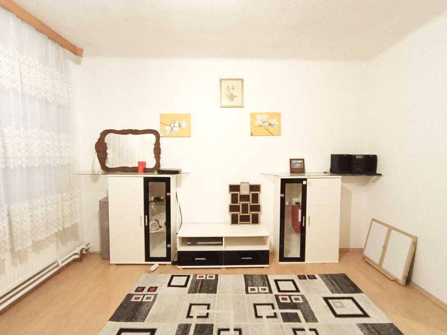 Helles Wohnzimmer mit Laminatboden, weiß gestrichenen Wänden und modernen Möbeln.