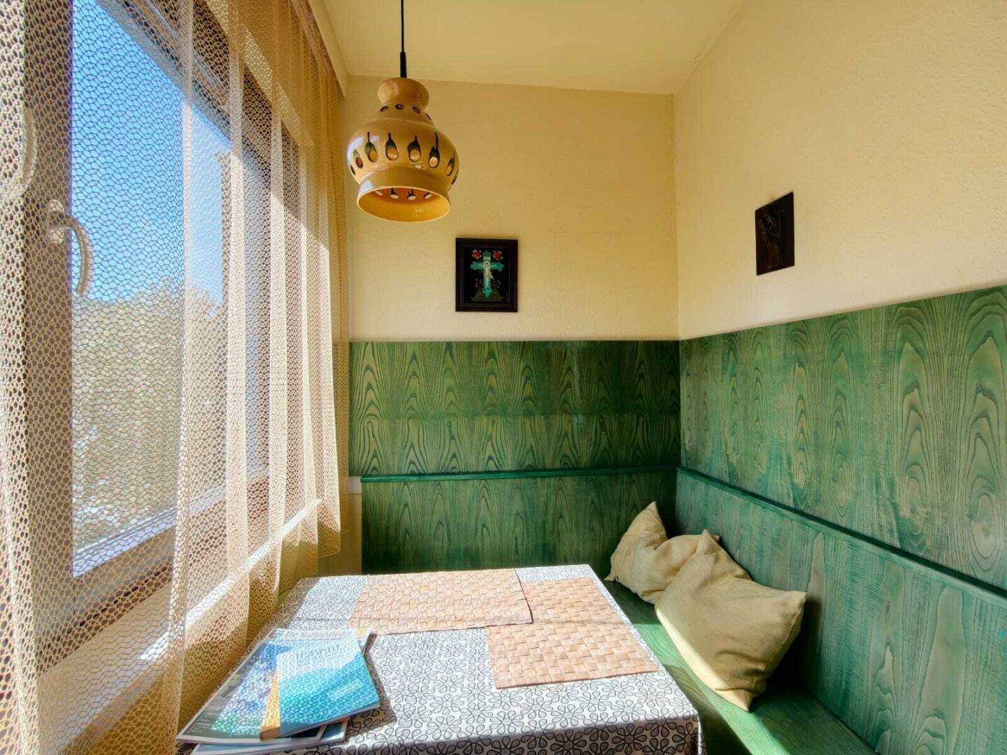 Gemütlicher Essbereich mit Holzbänken, einem Tisch und einem Fenster, das viel Tageslicht hereinlässt.
