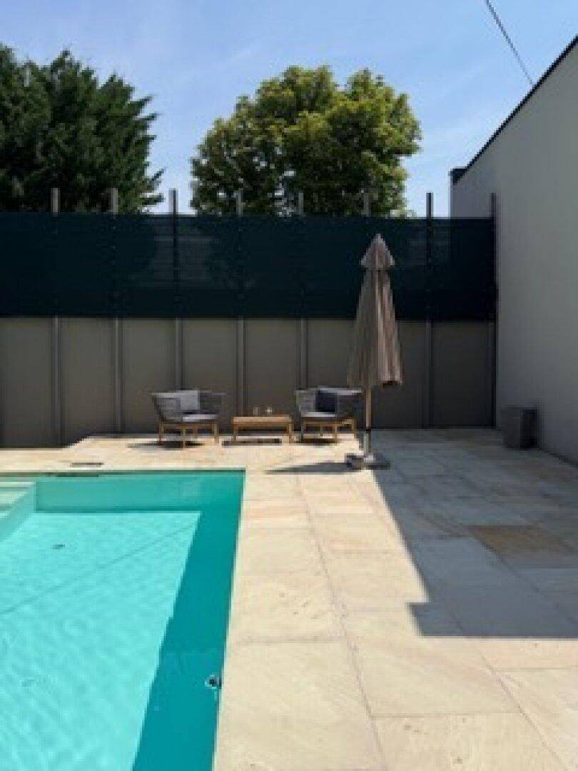 Entspannungsbereich am Pool mit bequemen Sitzgelegenheiten und Sonnenschirm auf der Terrasse.