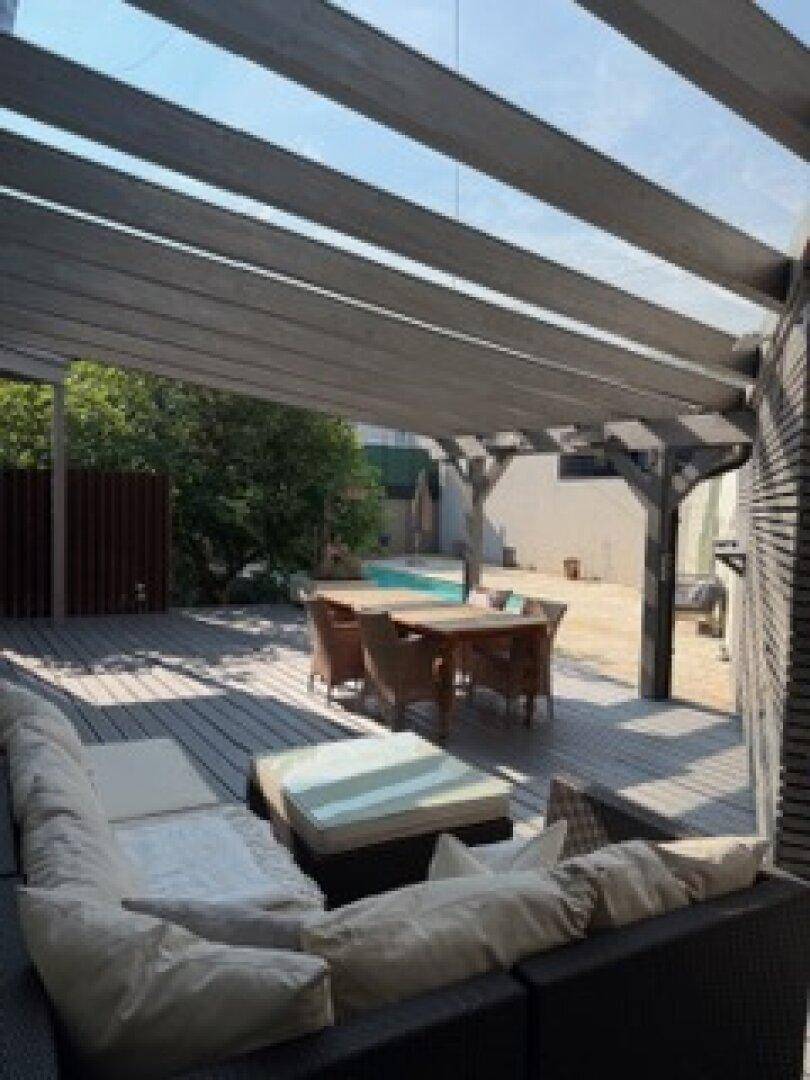 Geräumige Holzterrasse mit Lounge-Möbeln und Blick auf den angrenzenden Poolbereich.