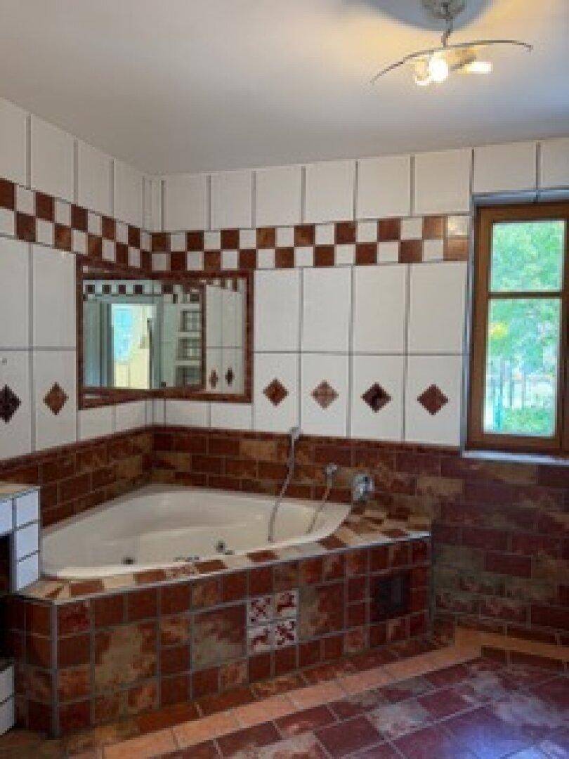 Badezimmer im traditionellen Stil mit Eckbadewanne und Fliesen in Terrakotta und Weiß.
