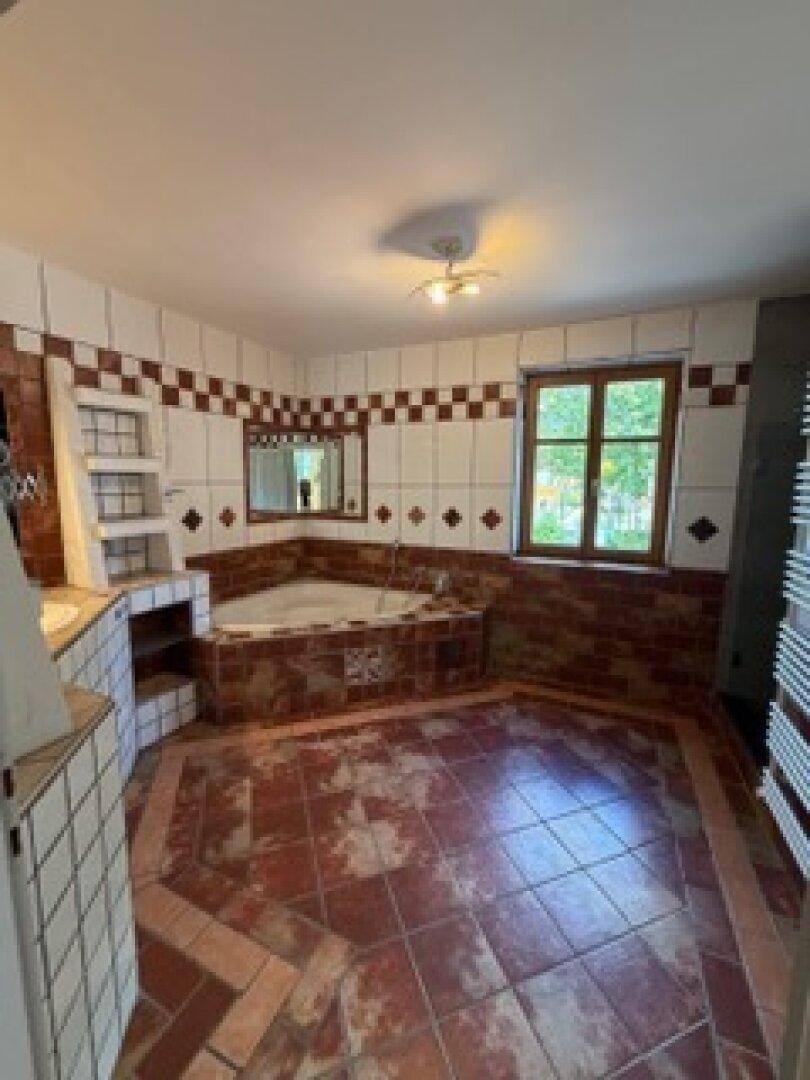 Geräumiges Badezimmer mit Eckbadewanne, Terrakotta-Fliesen und beheiztem Handtuchhalter.