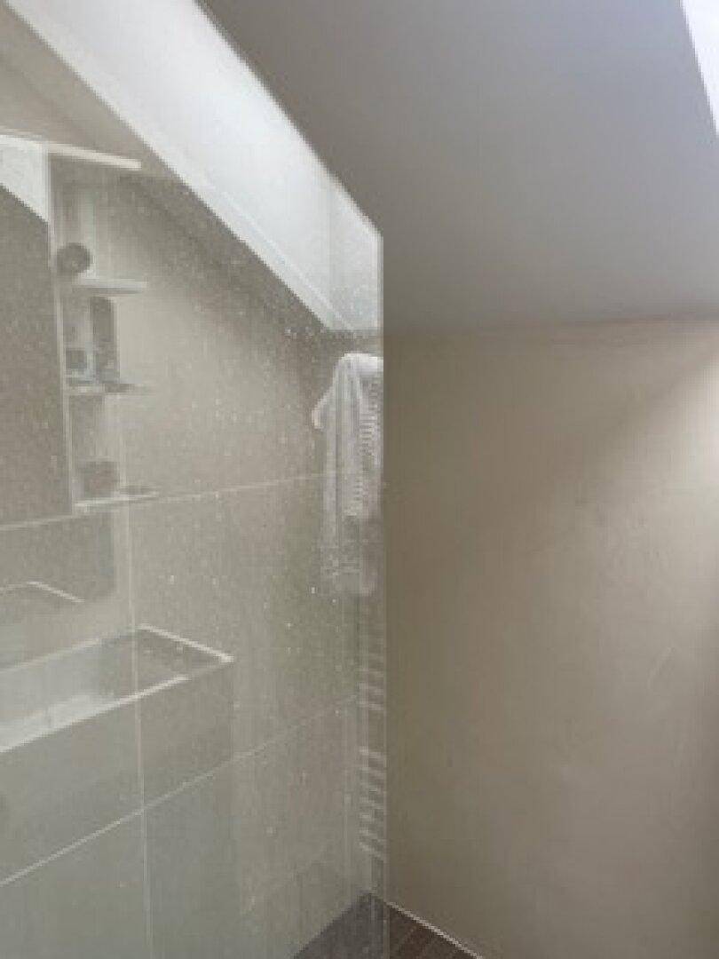 Modernes Badezimmer mit begehbarer Dusche, Glasabtrennung und einem beheizten Handtuchhalter.