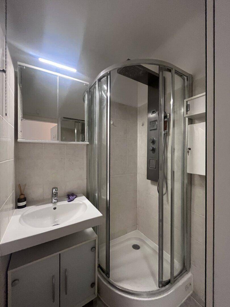Kleines Badezimmer mit Duschkabine, Waschbecken und Spiegelschrank.
