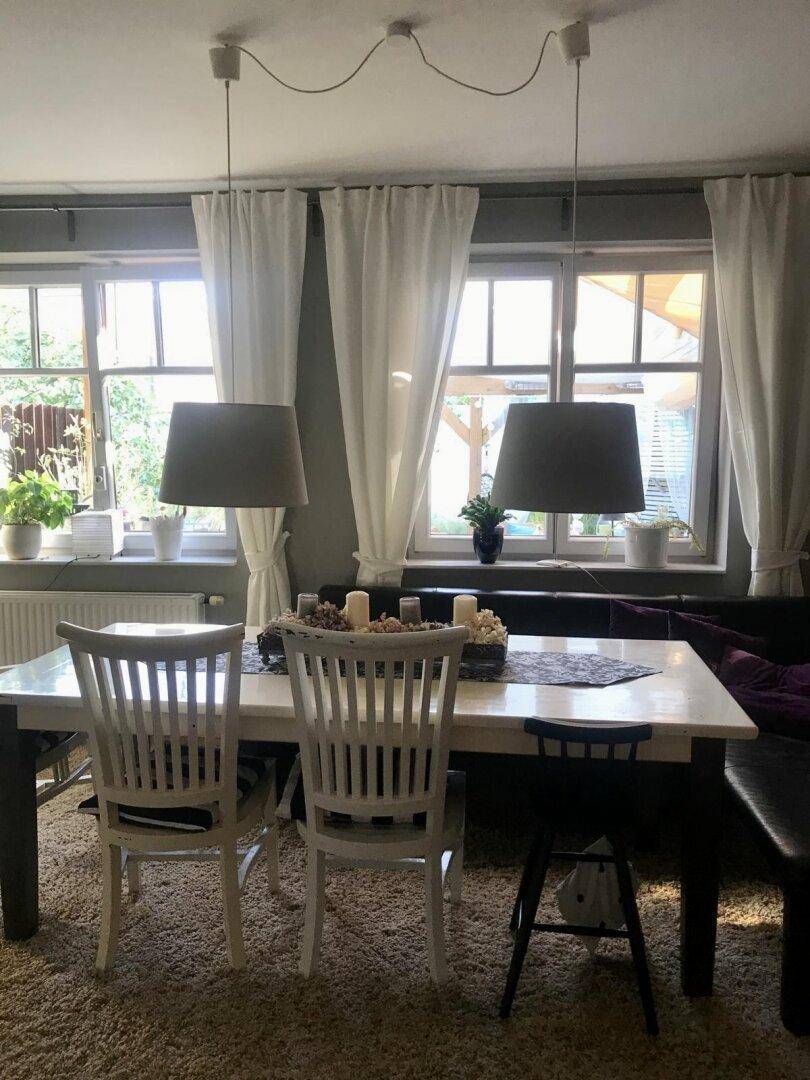 Heller Essbereich mit großem Esstisch, bequemen Stühlen und Blick ins Grüne durch die Fenster.