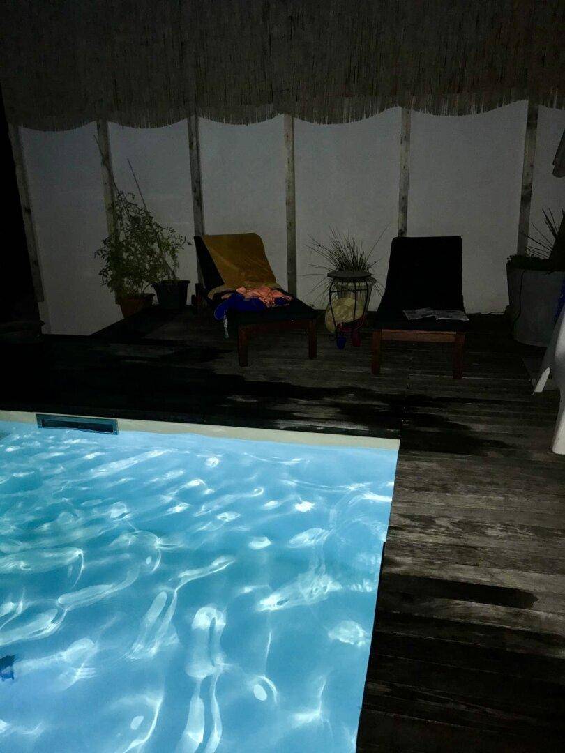 Beleuchteter Poolbereich bei Nacht mit Liegestühlen und entspannter Atmosphäre.