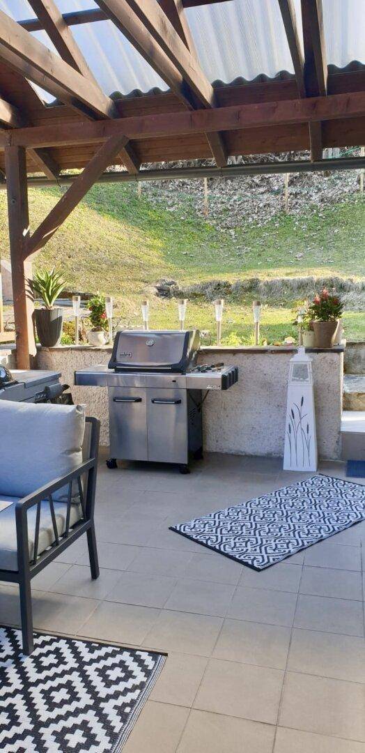 Überdachte Terrasse mit Grillbereich und Blick auf den angrenzenden Garten.