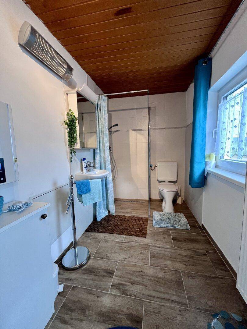 Modernes Badezimmer mit Duschkabine, Holzdecke und Fenster.