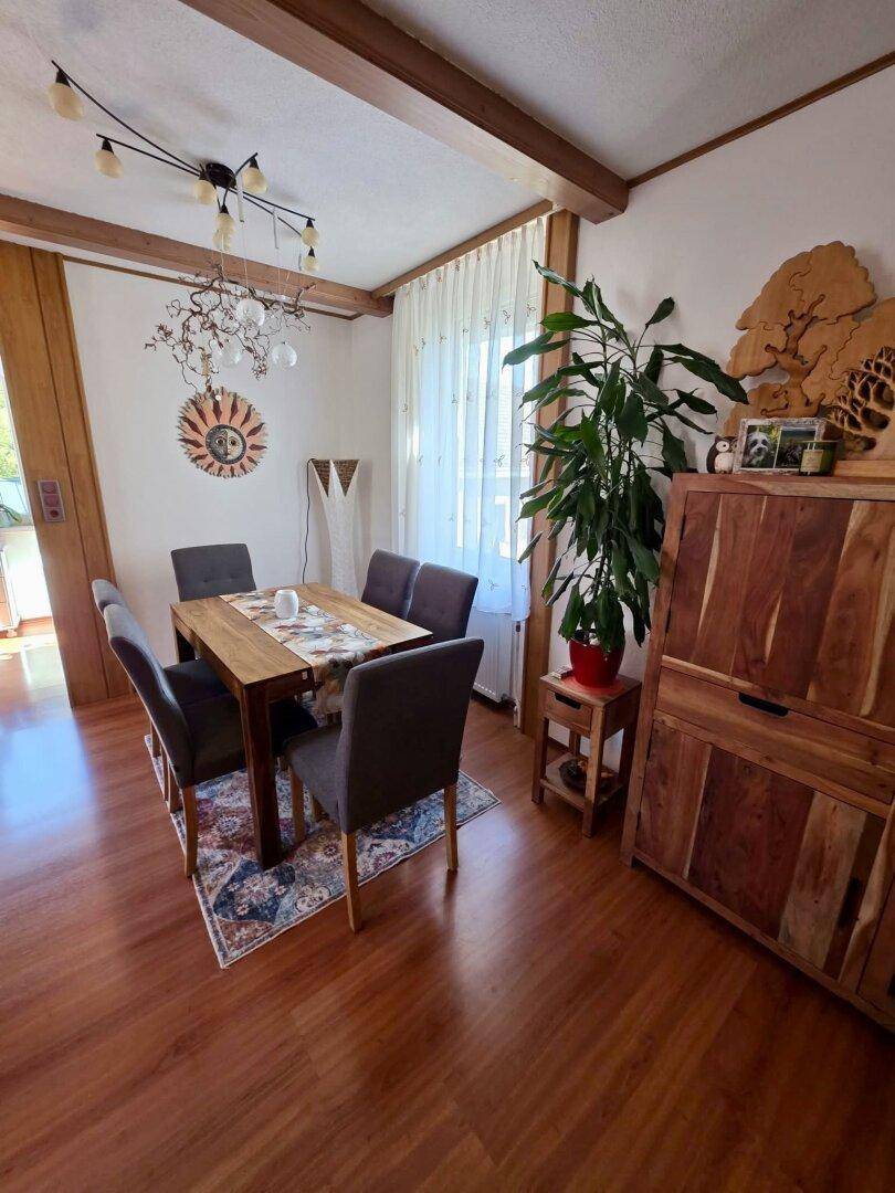 Heller Essbereich mit Holztisch, passenden Stühlen und dekorativer Wandkunst.