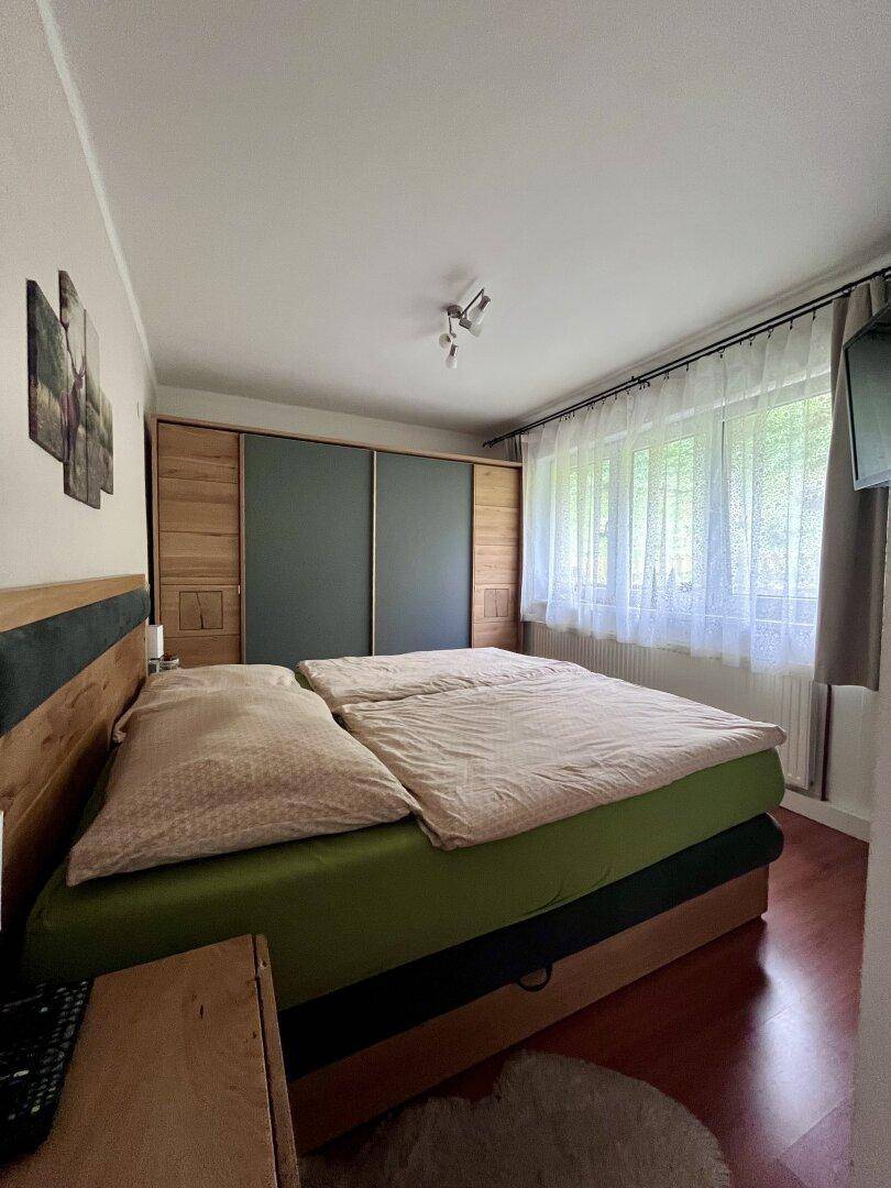 Schlafzimmer mit Doppelbett, großem Kleiderschrank und Blick ins Grüne.