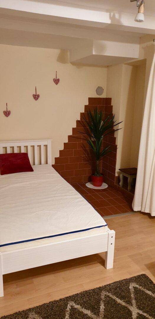 Einfaches Schlafzimmer mit Einzelbett und dekorativer Ziegelwand im Hintergrund.