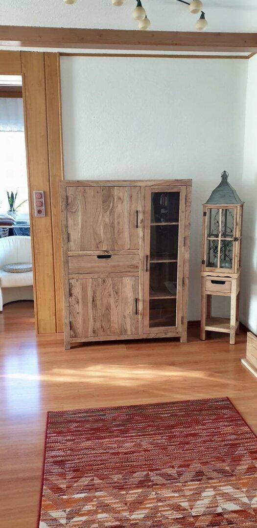 Flur mit Holzschrank und Teppich, der zu weiteren Räumen führt.
