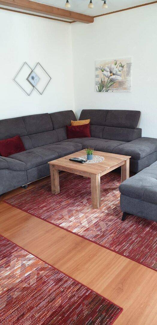 Helles Wohnzimmer mit großem Ecksofa, Holztisch und moderner Dekoration.