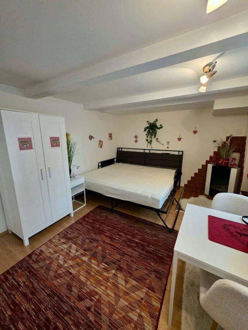 Schlafzimmer mit Doppelbett, Kleiderschrank und Essbereich in einem Raum.
