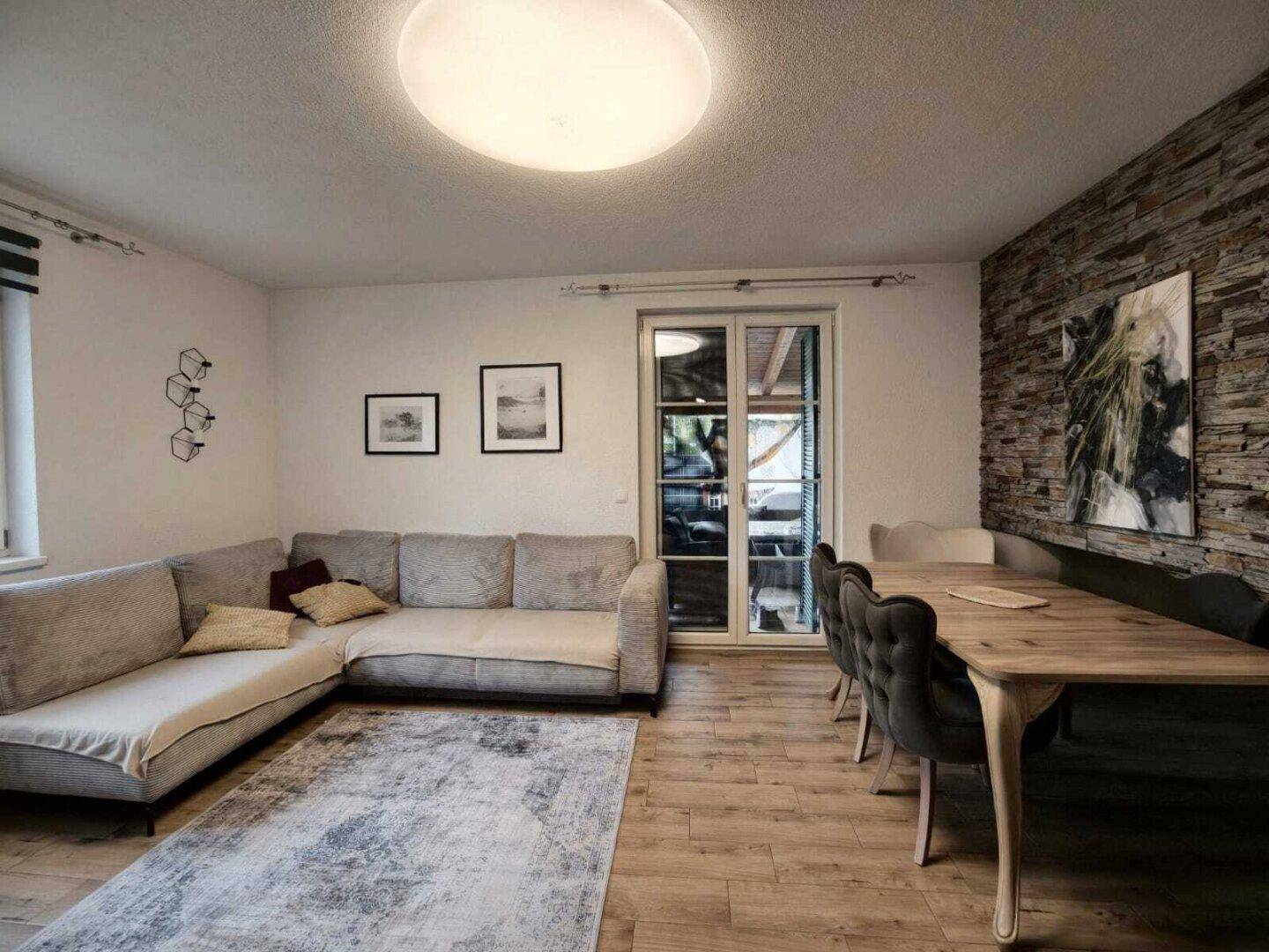 Heller Wohn- und Essbereich mit Holzboden, bequemer Couch und großem Esstisch.