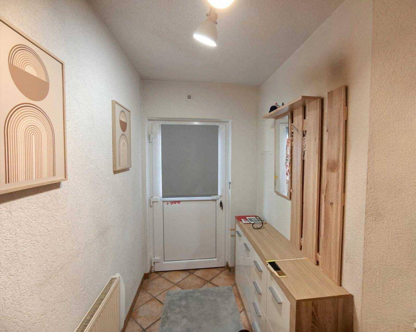 Eingangsbereich mit Fliesenboden, Garderobe und moderner Wanddekoration.