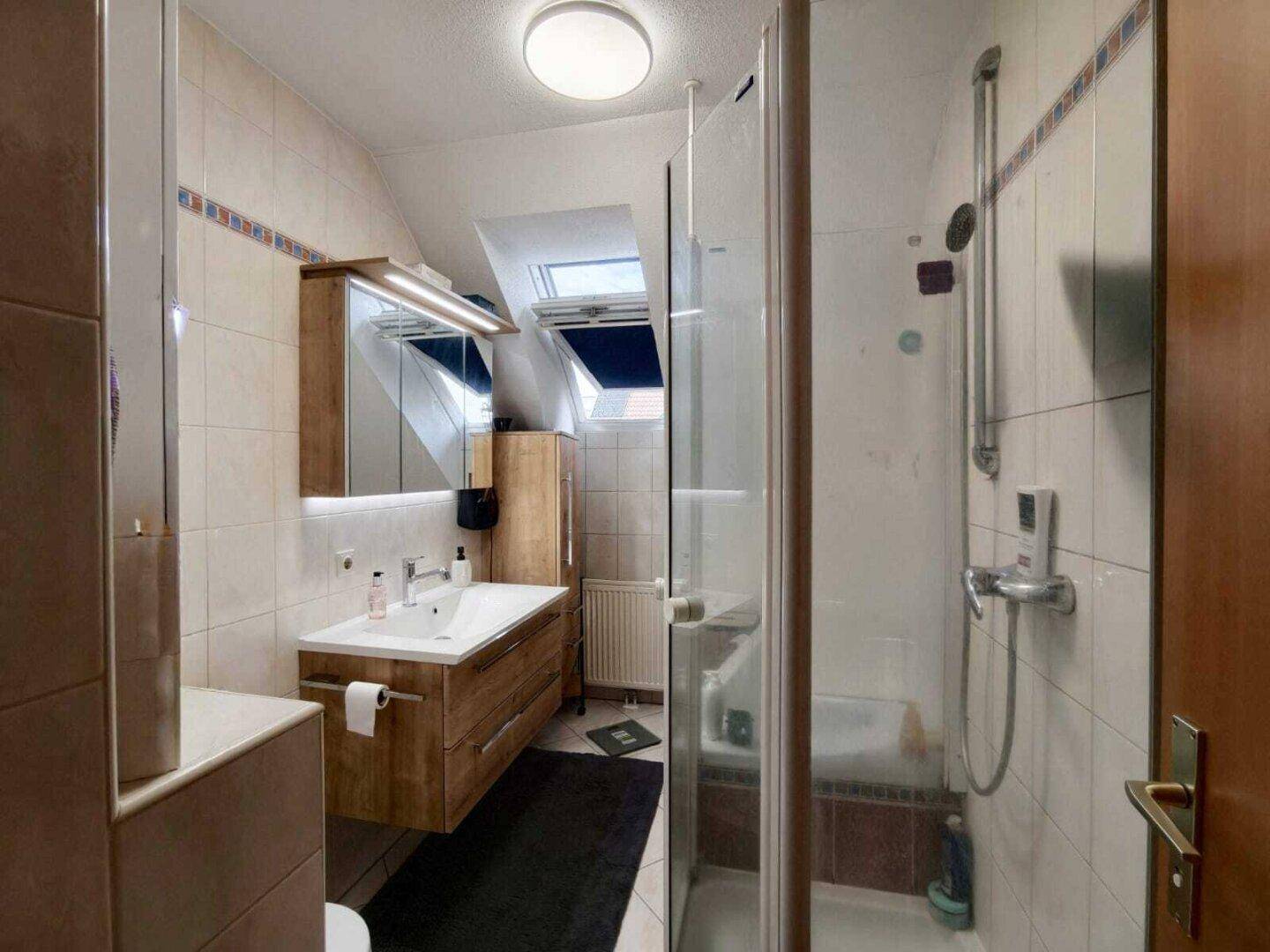 Modernes Badezimmer mit Dusche, Waschtisch und Dachfenster für natürliches Licht.