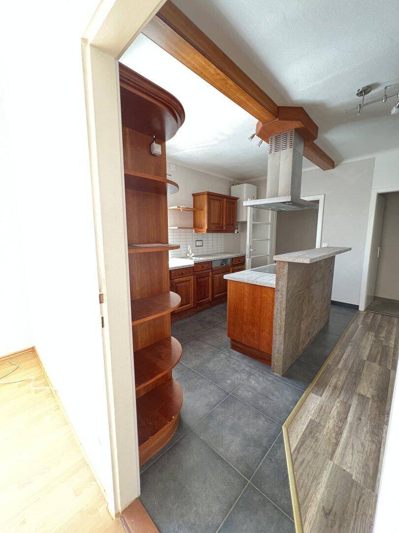 Offene Küche mit Holzschränken, integrierten Geräten und einer praktischen Theke, die zum Wohnbereich übergeht.