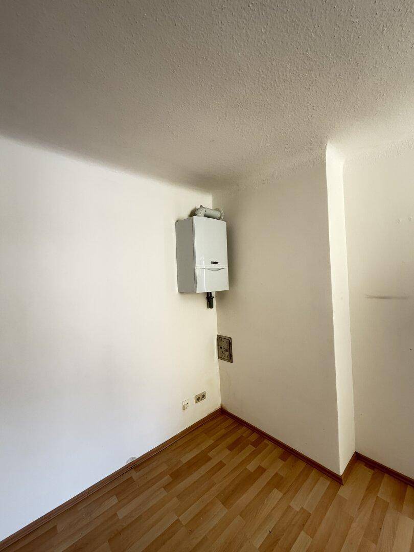Nahaufnahme eines an der Wand montierten Heizkessels in einem leeren Raum, funktional und platzsparend.