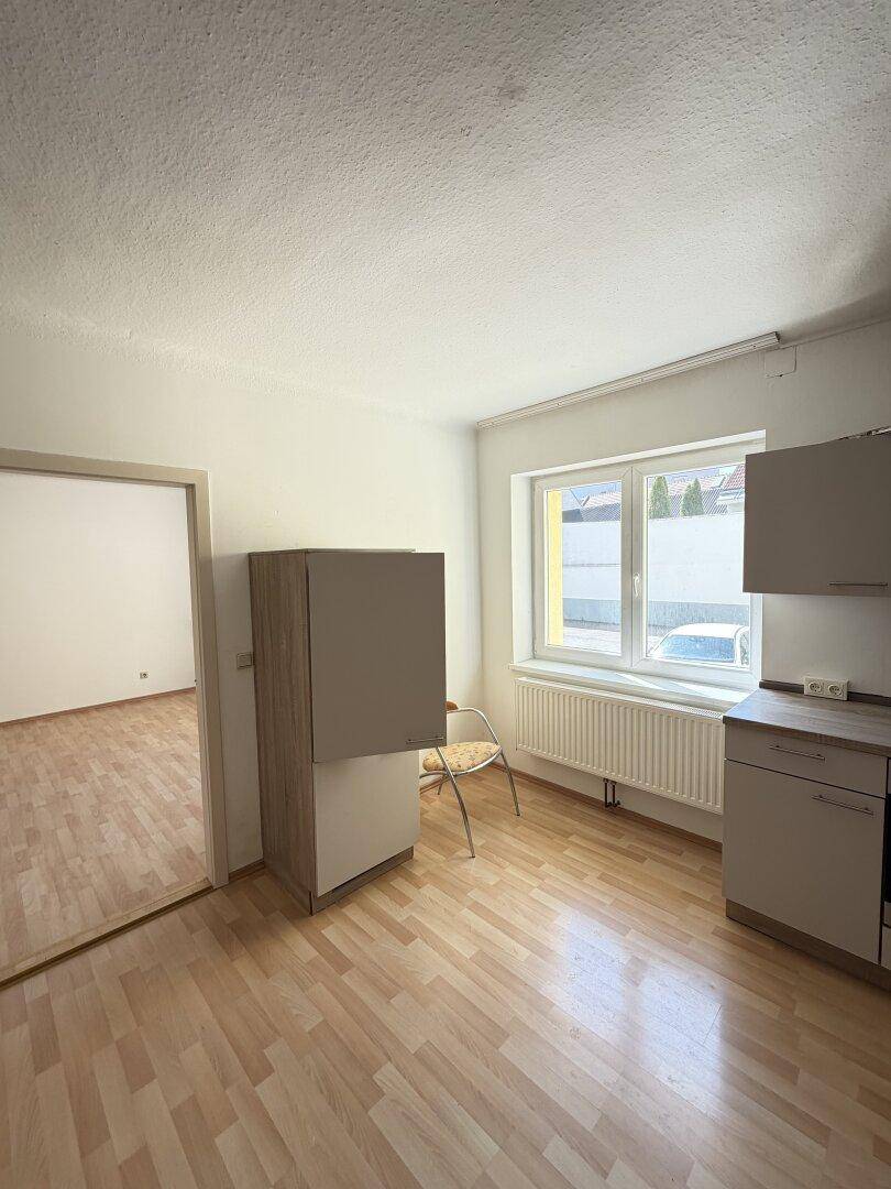 Heller Küchenbereich mit Laminatboden und Blick aus dem Fenster, bereit zur individuellen Gestaltung.