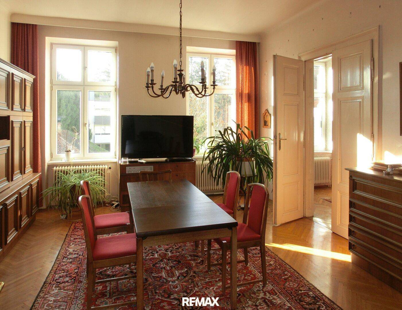 Heller Essbereich mit Holztisch, Stühlen und Blick auf den Garten durch große Fenster.