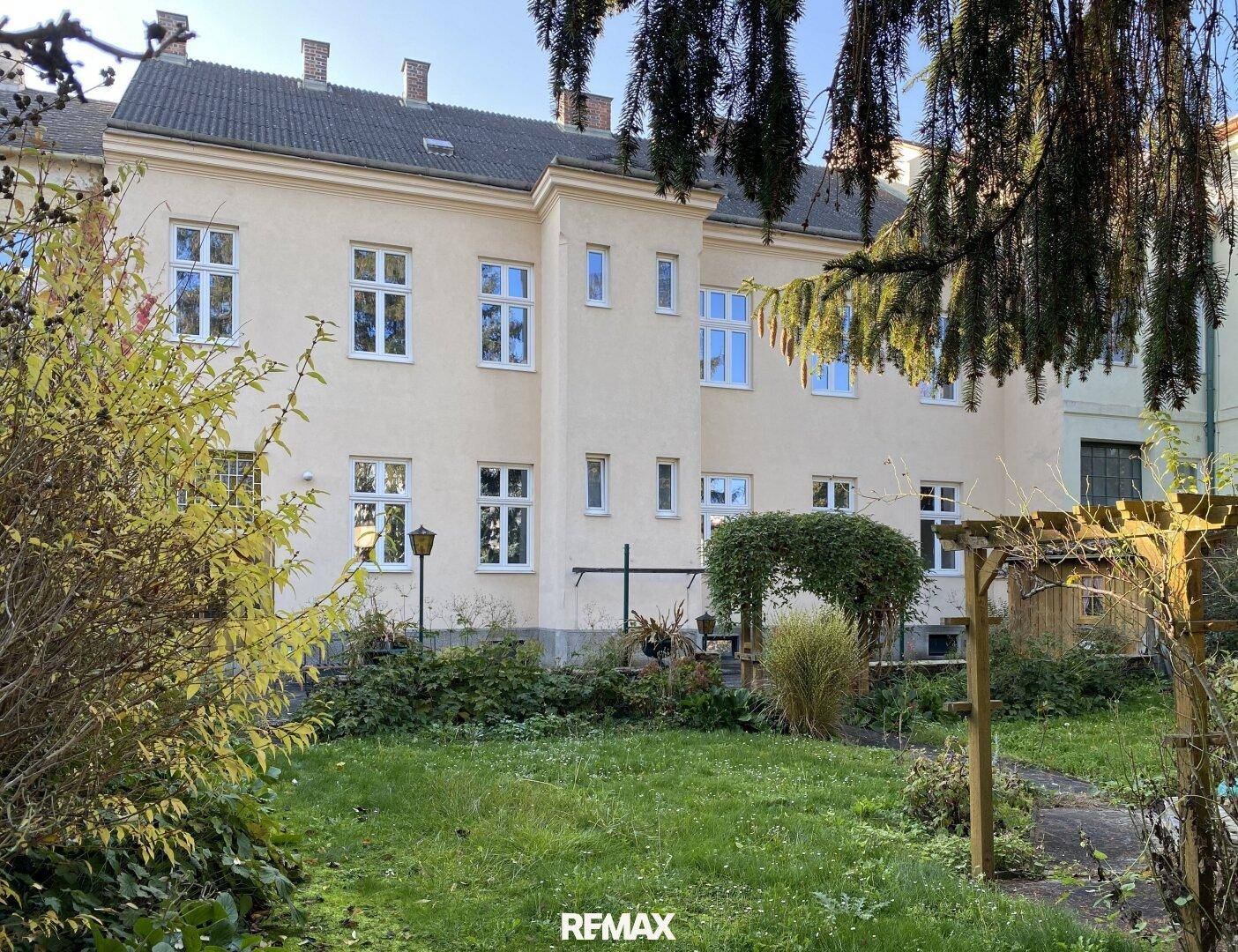 Hinterer Gartenbereich mit Rasen, Bäumen und der Rückseite des Gebäudes.